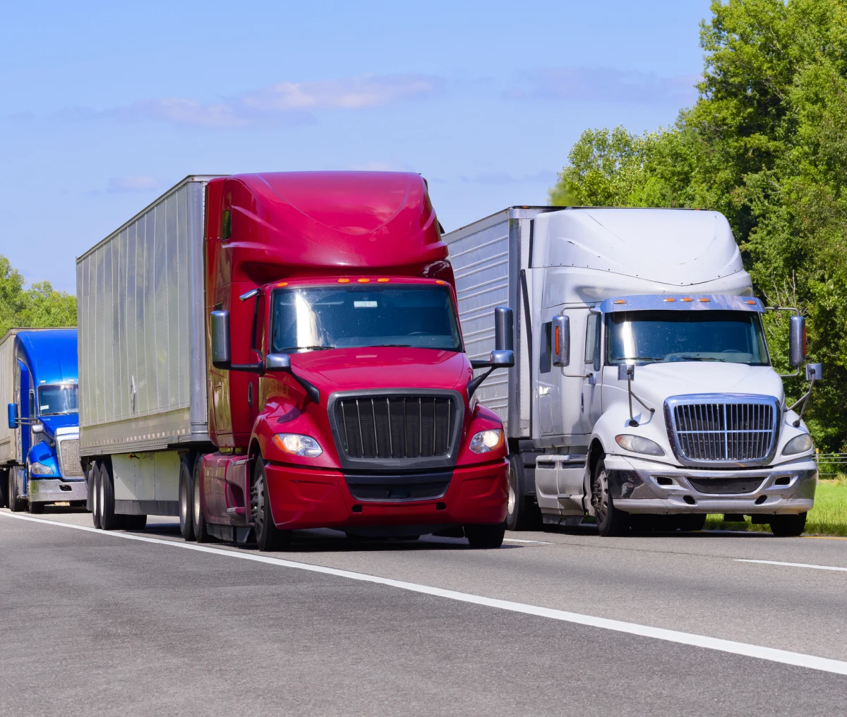 Red, silver, and blue trucks on highway